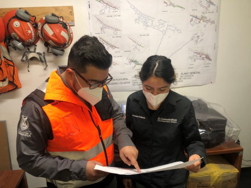 Female Miner at Cementation Two workers in wearing personal protective equipment looking at document